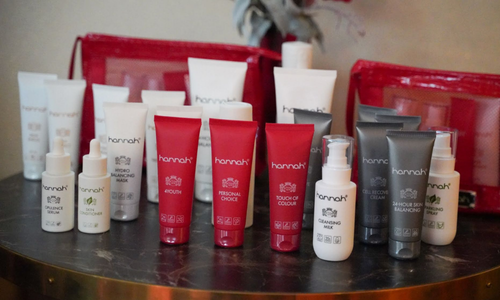 Een uitgebreide collectie huidverzorgingsproducten van het merk hannah, bestaande uit diverse tubes en flacons met crèmes, serums en reinigingsproducten, gepresenteerd op een tafel.