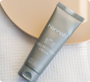 hannah cell recovery cream tube schuin liggend op een ronde schaal en een witte handdoek