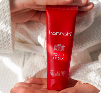 hannah touch of silk rode tube vastgehouden in handen tegen een witte badjas