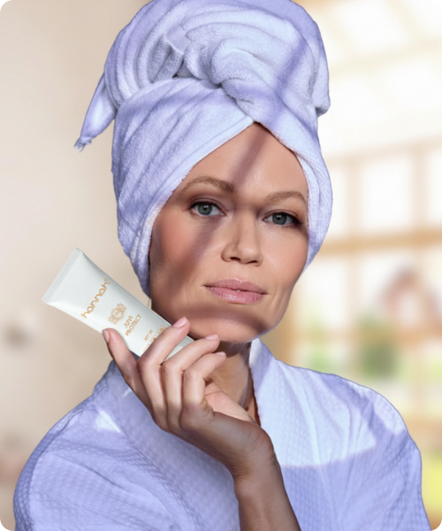 Vrouw met een handdoek om haar hoofd die hannah juvi protect zonnebrandcrème toont.