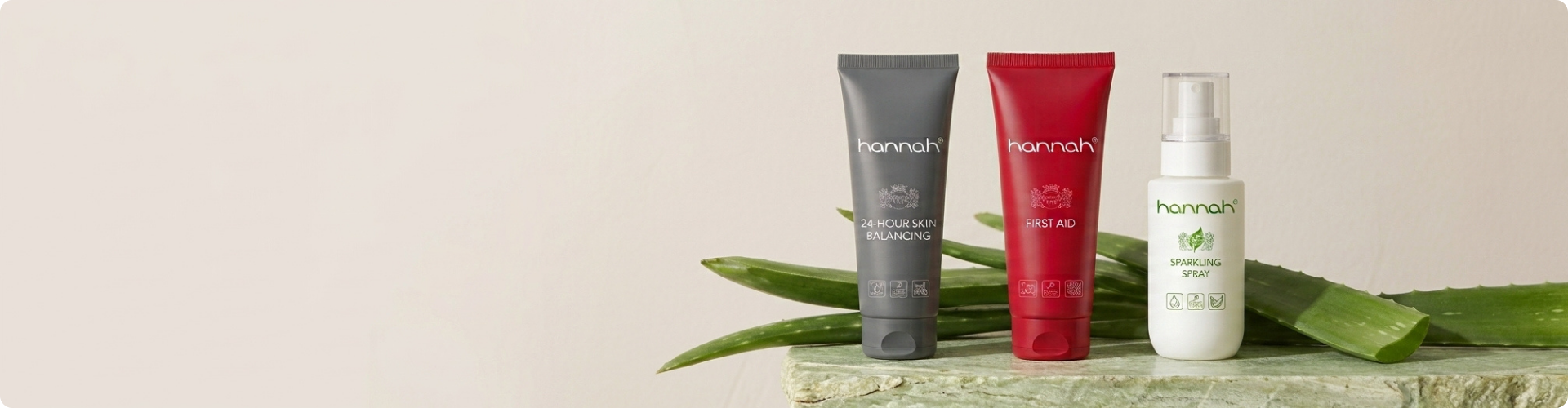 hannah producten 24 hour skin balancing first aid en sparkling spray op stenen plateau met aloe vera bladeren op de achtergrond