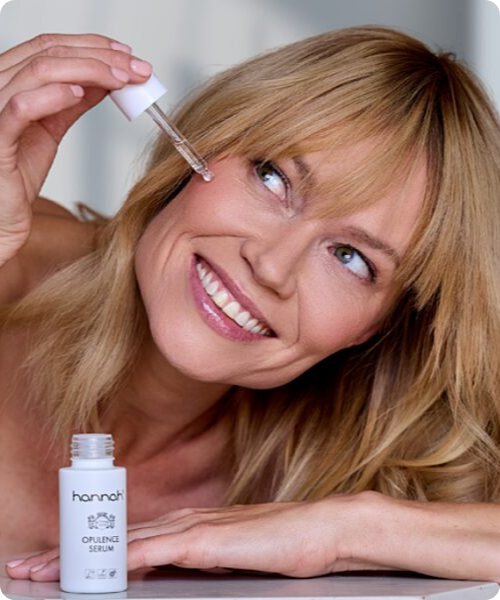 Vrouw die een druppel hannah opulence serum aanbrengt op haar gezicht met een pipetje.
