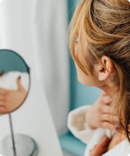 vrouw in badjas kijkt in de spiegel voor hannah anti aging verzorging