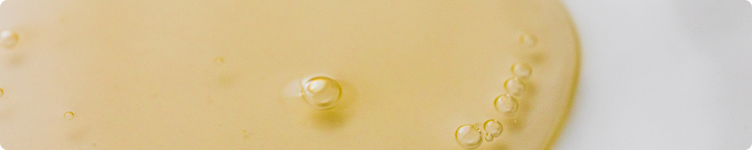 Close-up van de rijke, goudgele textuur van vitamine E olie met zichtbare luchtbellen.